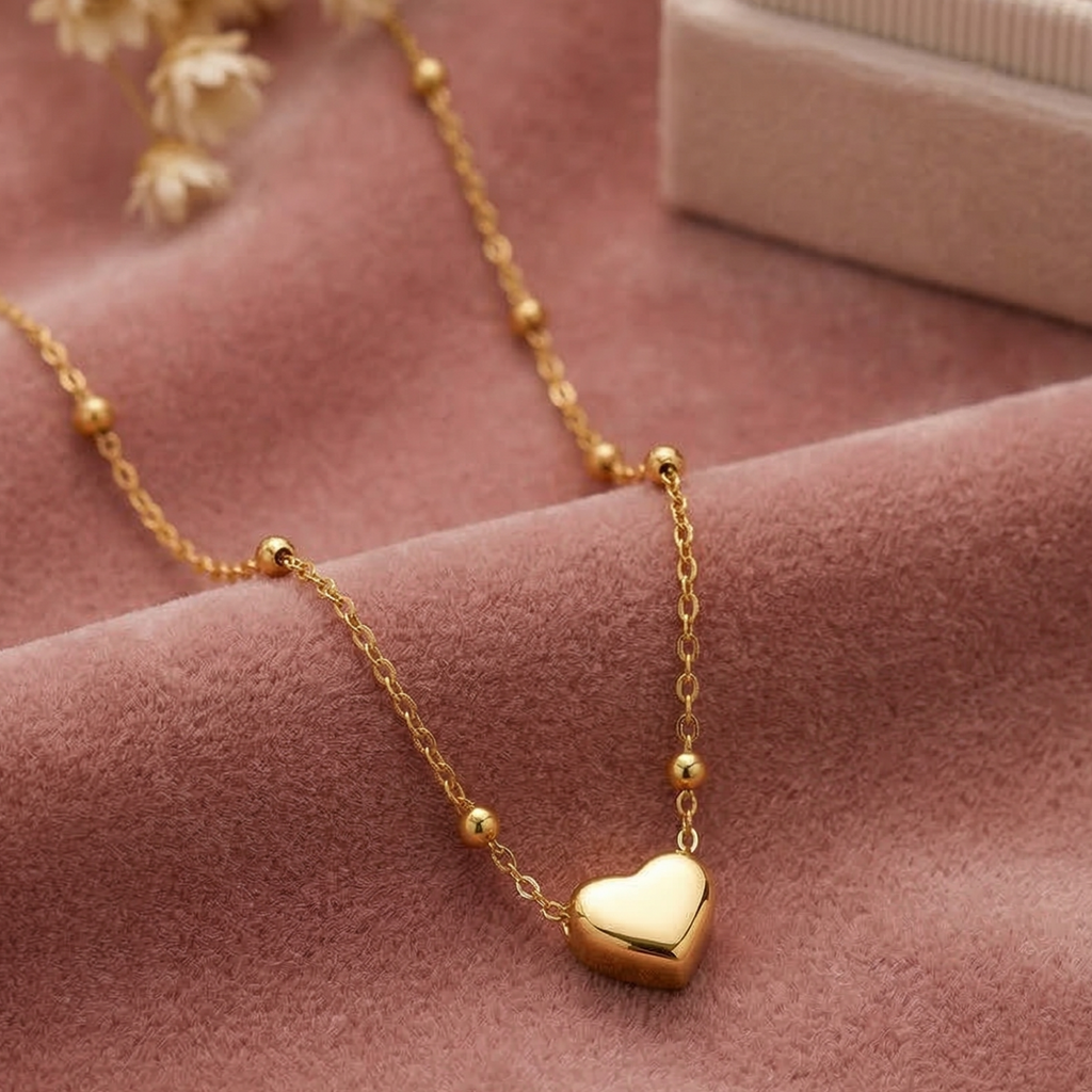 Gold necklace with a heart pendant on a pink fabric background