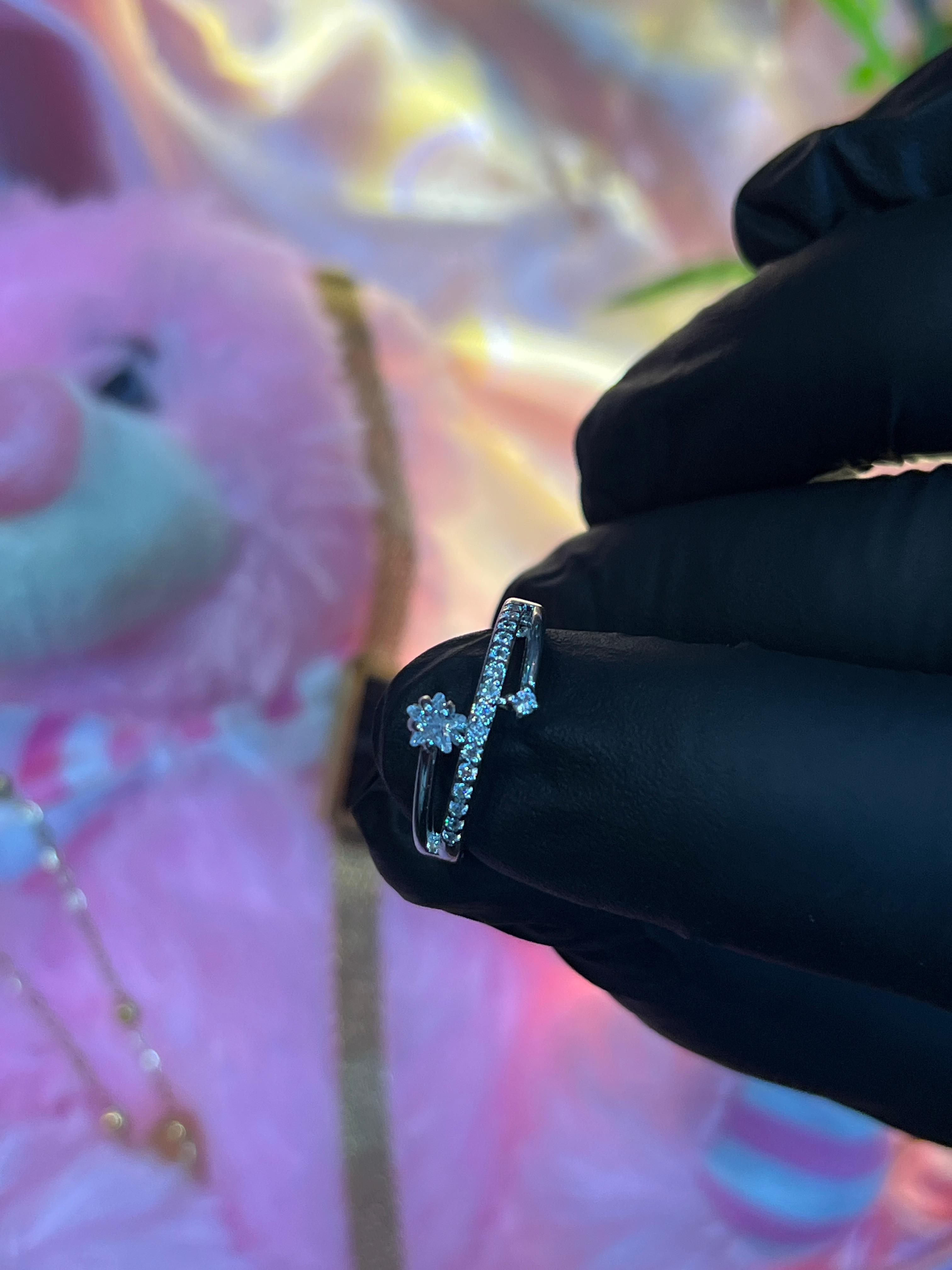 Silver ring with a diamond on a black gloved hand against a colorful background